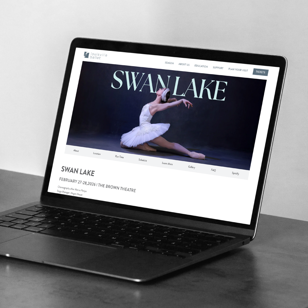 A laptop displays a website for the ballet Swan Lake, showing an image of a ballerina in a white tutu performing on stage, along with event details for a performance at The Brown Theatre.