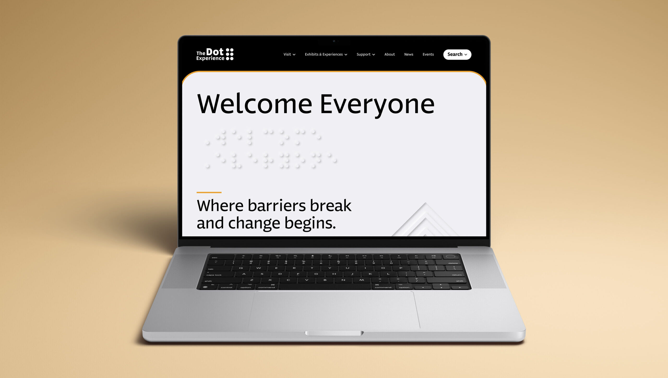 A laptop on a beige surface displays a website with the text “Welcome Everyone” and “Where barriers break and change begins.” Braille dots are visible below the welcome message.