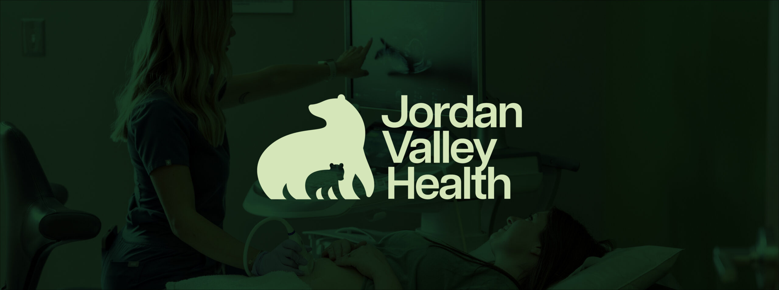 A healthcare worker performs an ultrasound on a patient, with the Jordan Valley Health logo featuring a bear and cub centered over the image.